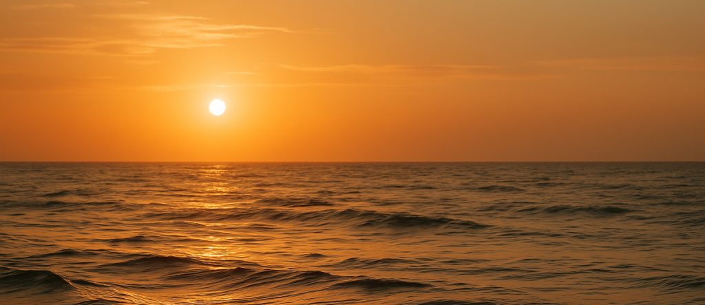 Sunlight breaking through clouds over a calm sea, symbolizing peace after storm.
